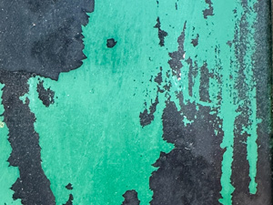 Dark metal surface with scraped green paint