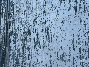 Wood surface with white paint scraped and peeling
