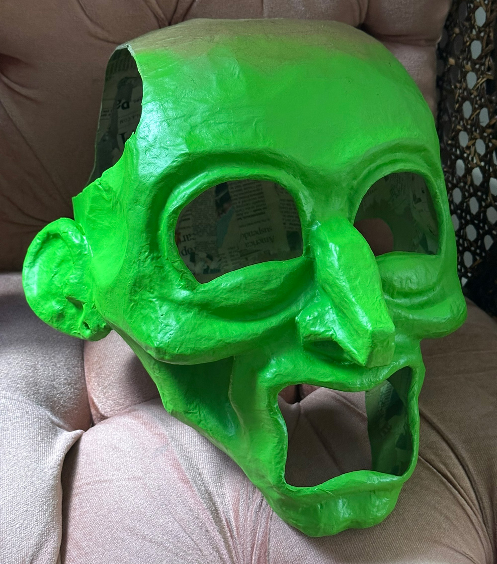 The head spray with eye and mouth holes cut out, and painted green
