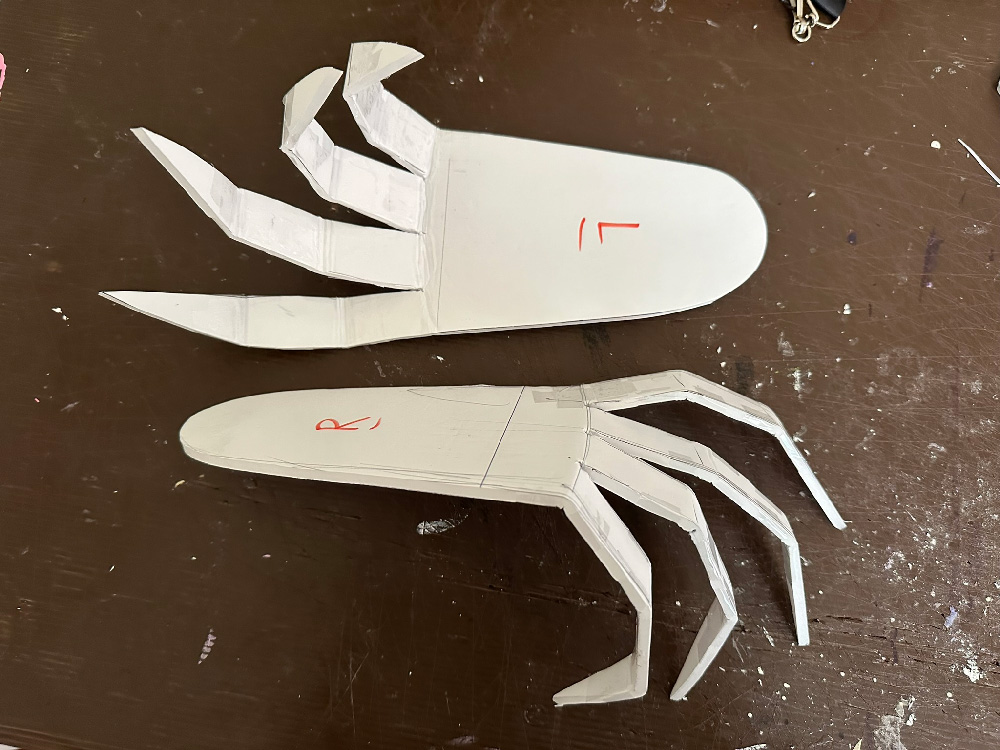 Gargoyle feet cut out of flat foam board, they're long and narrow with longp pointed toes. The joints of the toes have been bent.