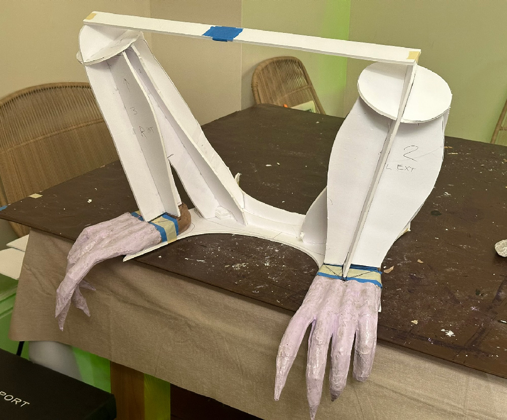 Crouched legs made of flat foam board shapes in a primitive sort of armature. The sculpted gargoyle feet are below.