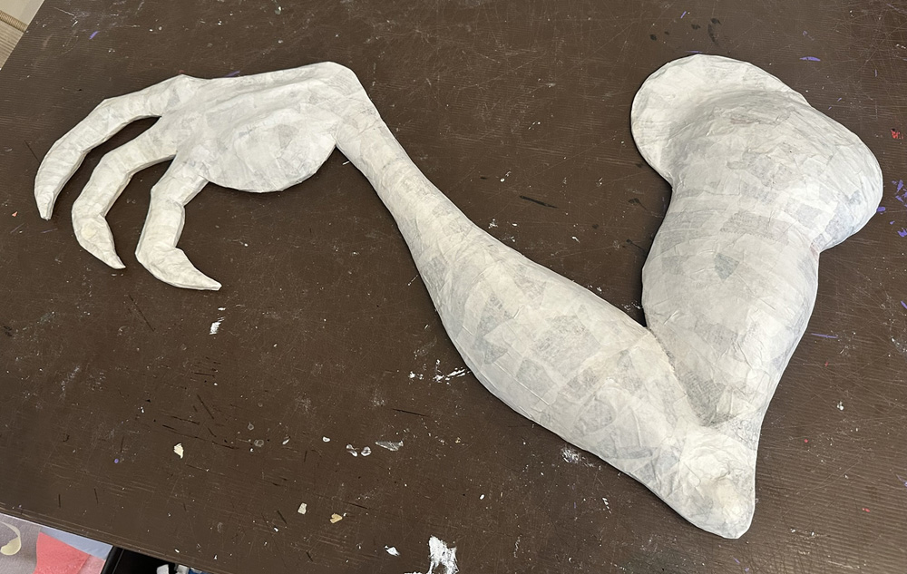 The arm is now covered in white paper mache.