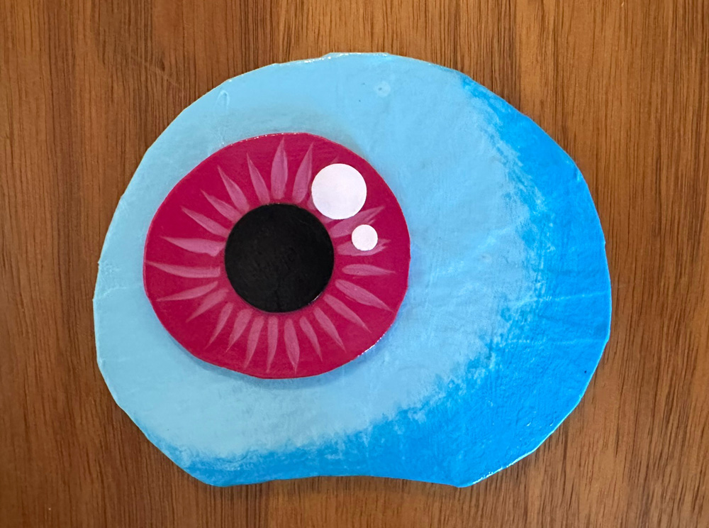 Close up of the Jabberwocky's eye; it's light blue with a dark pink iris and black pupil.