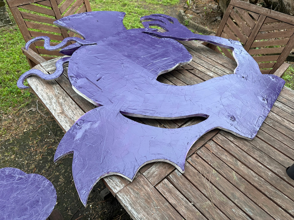 The head/neck/arm/wings component of the Jabberwocky, laying upside down with the back surface spray-painted dark purple.