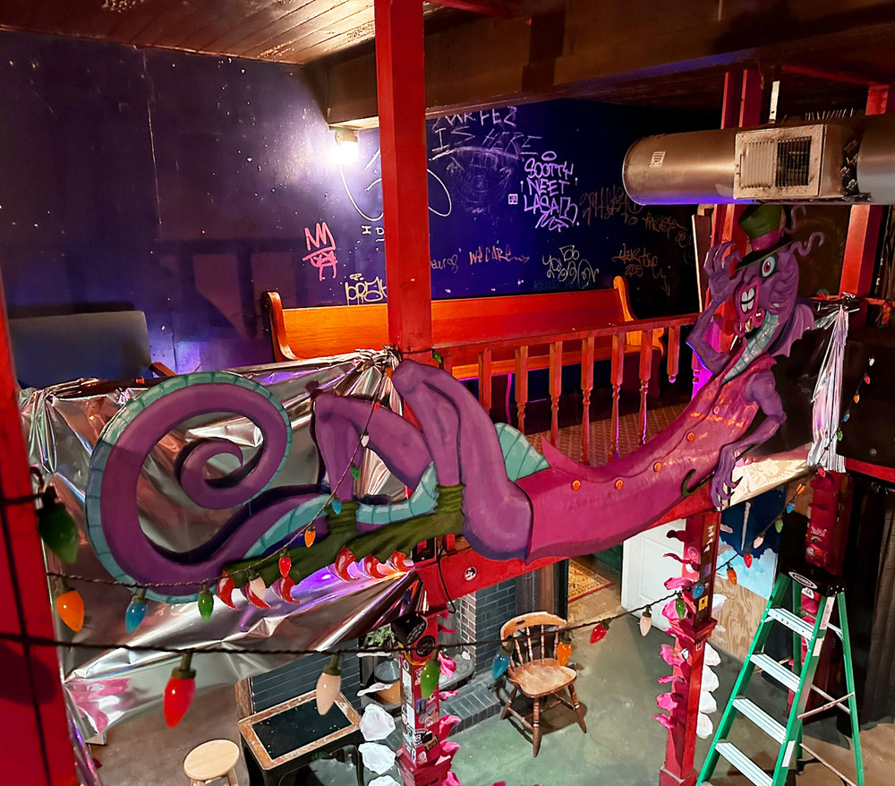 The Jabberwocky sculpture hanging along the upstairs railing of a bar in daylight, the morning of the wedding.