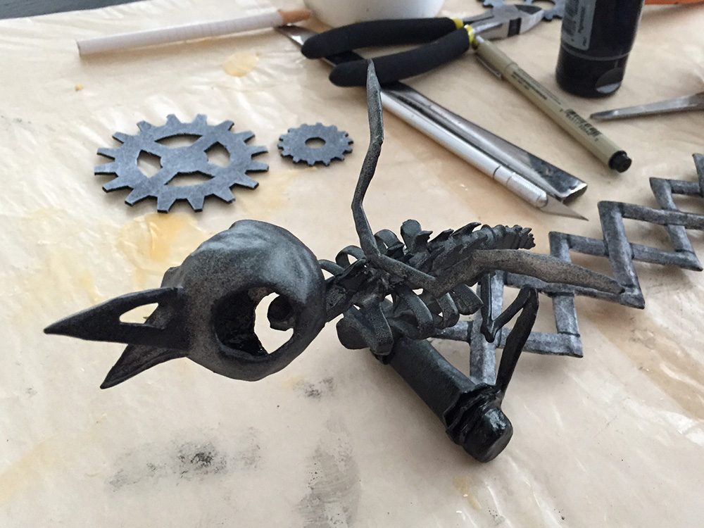 Applying a light dusting of black spray paint to the bird skeleton