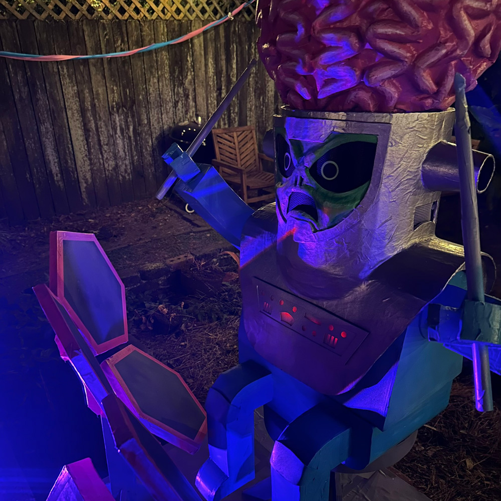 Big brain alien playing a set of hexagonal electronic drums