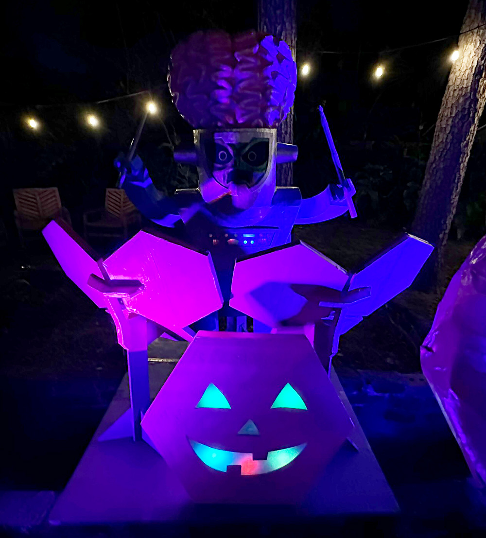 Nighttime view of the alien set up at his drums; the bass drum jack o' lantern face is lit up.