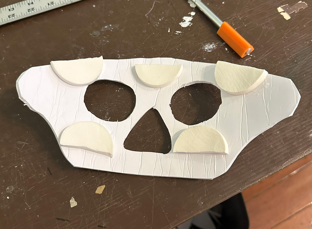 Rough face shape cut out from foam board with eyes and nose holes