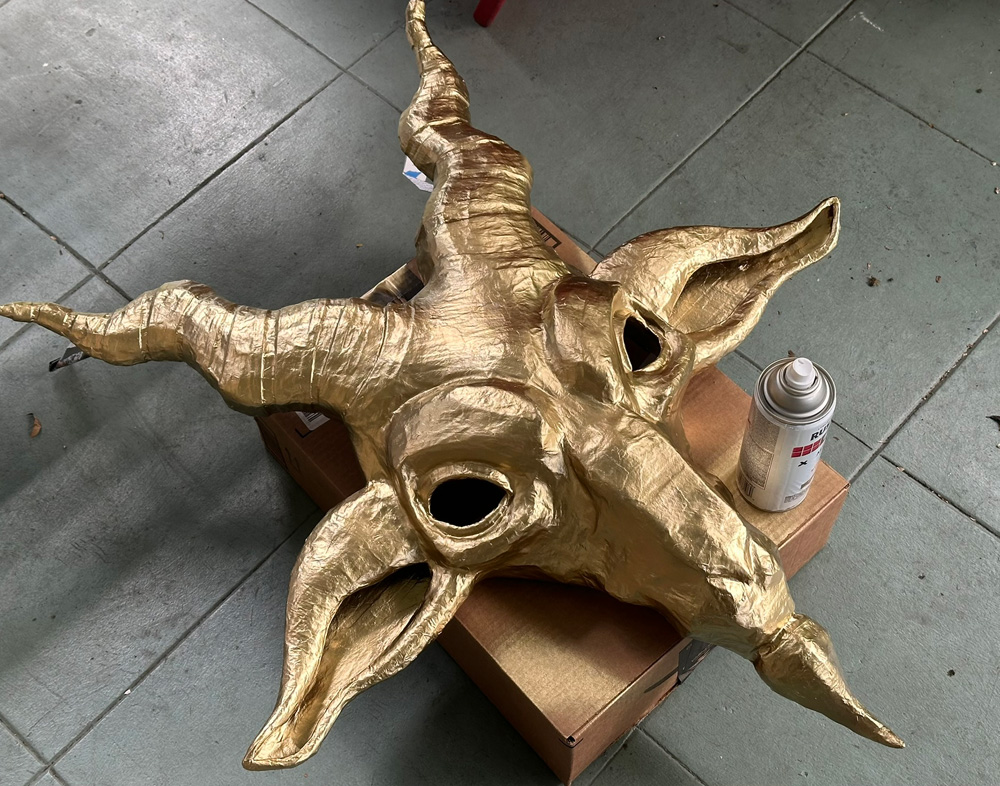 The goat head by itself, freshly spray painted gold, sitting on my porch to dry.