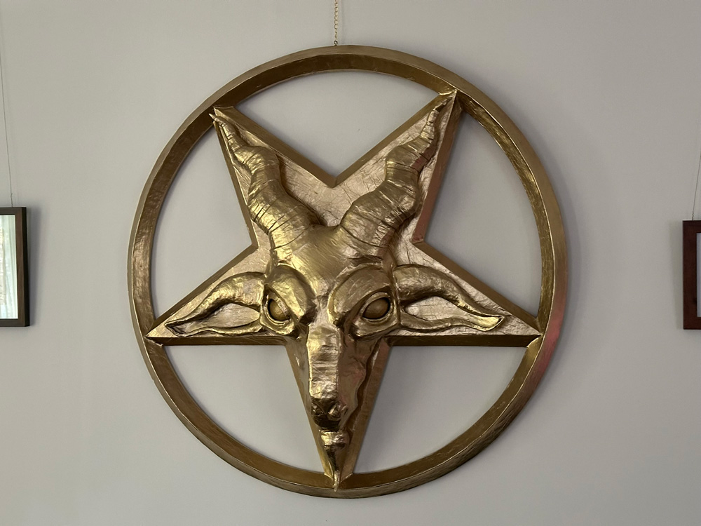 The completed gold pentagram with goat head hanging on my wall in the daytime.