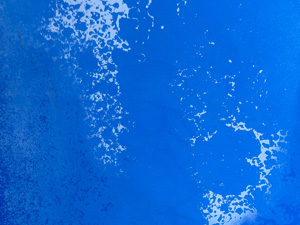 Weathered bright blue paint on a metal surface, with some corrosion that's white-ish and some that's a darker blue.