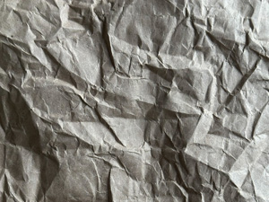 Crumpled brown paper texture in dramatic evening lighting.