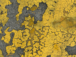 Very cracked yellow paint with some missing chunks, on the street.