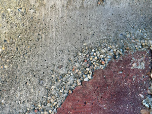 Gray concrete with a broken-off corner that was repaired with red concrete